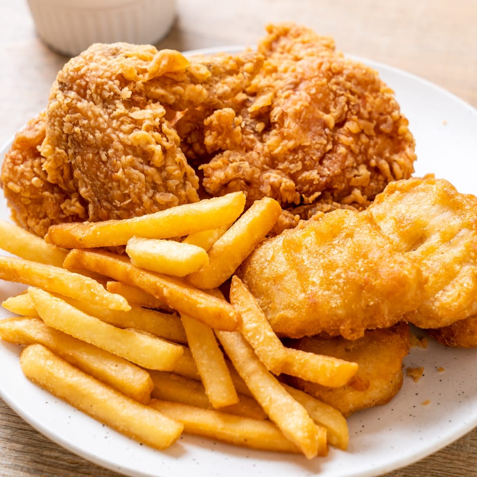 A plate of crispy fried chicken, golden french fries, and chicken nuggets from The Hitching Post.