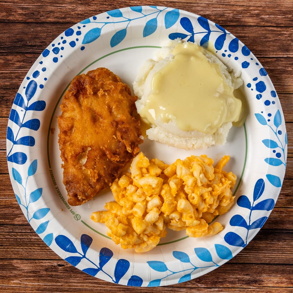 The Hitching Post's fried chicken, mashed potatoes with gravy, and macaroni and cheese on a paper plate.